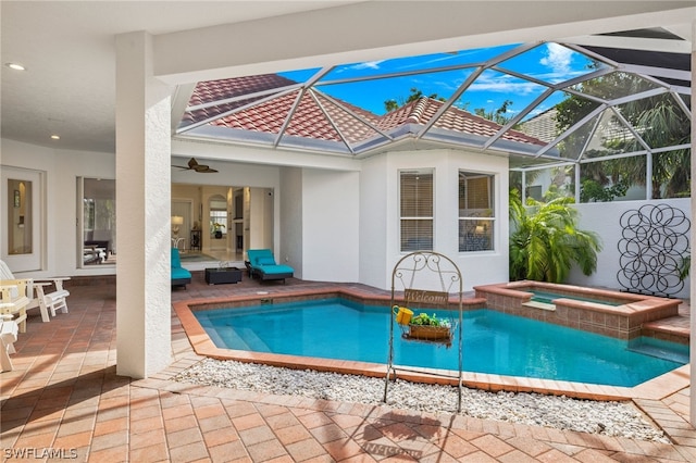 view of swimming pool featuring ceiling fan, a patio area, glass enclosure, and an in ground hot tub