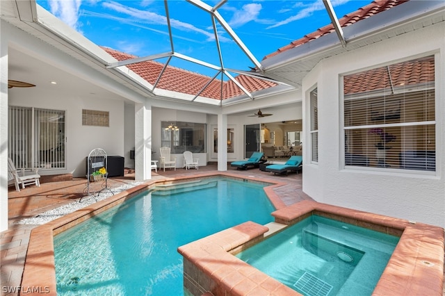 view of pool featuring ceiling fan, a patio area, glass enclosure, and an in ground hot tub