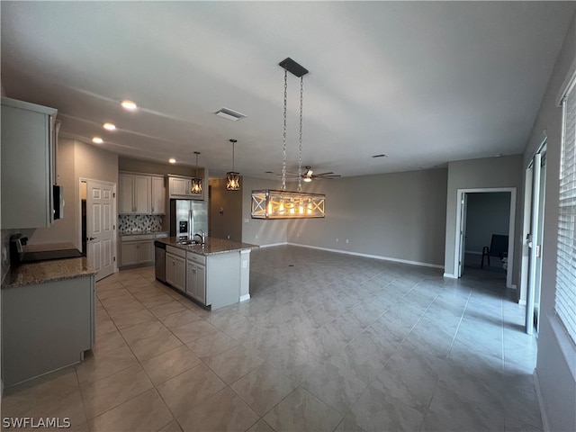 kitchen featuring pendant lighting, an island with sink, backsplash, ceiling fan, and stainless steel fridge with ice dispenser