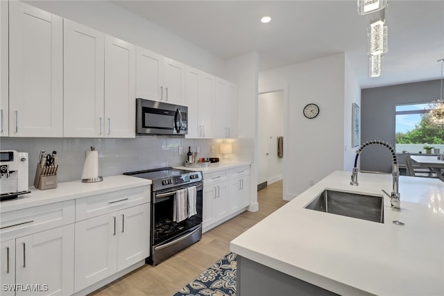 kitchen with electric range oven, backsplash, decorative light fixtures, light wood-type flooring, and white cabinetry