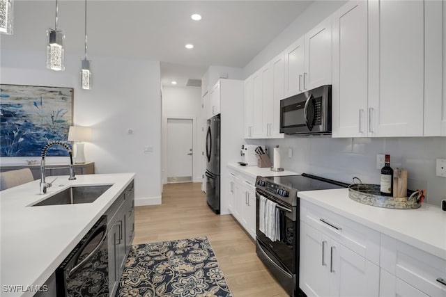 kitchen featuring light hardwood / wood-style flooring, white cabinets, black appliances, decorative backsplash, and sink