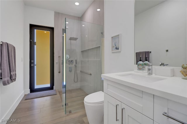 bathroom featuring a shower with shower door, vanity, hardwood / wood-style floors, and toilet