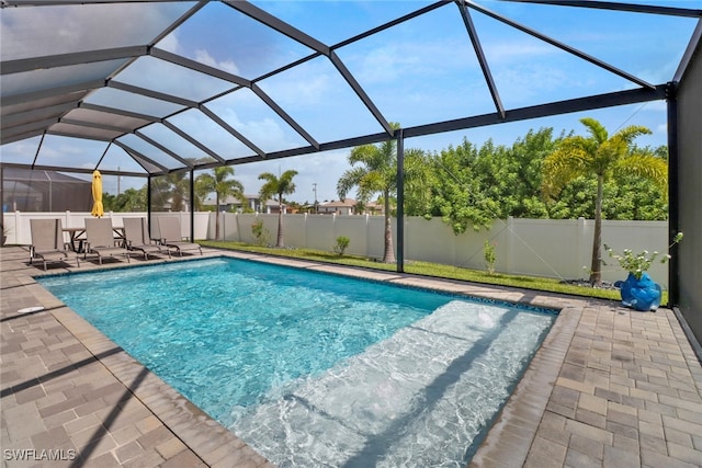 view of swimming pool featuring glass enclosure and a patio area