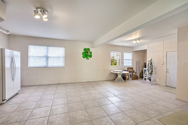 unfurnished room featuring light tile patterned flooring and beamed ceiling