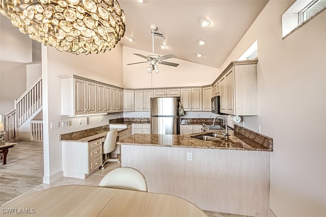 kitchen with appliances with stainless steel finishes, stone counters, high vaulted ceiling, sink, and kitchen peninsula