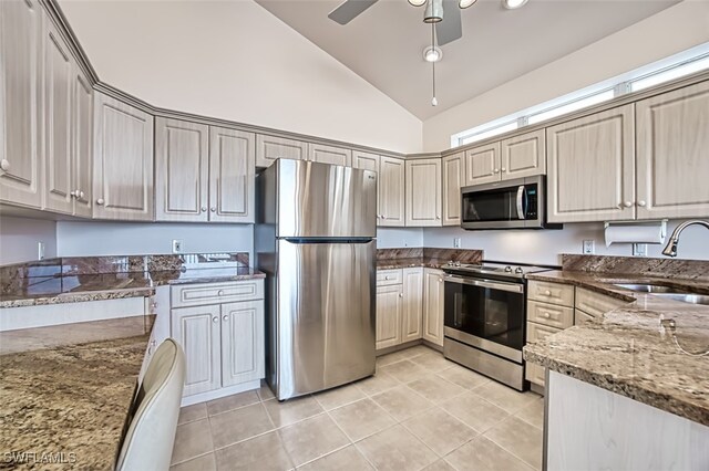 kitchen featuring dark stone counters, ceiling fan, stainless steel appliances, sink, and light tile patterned floors