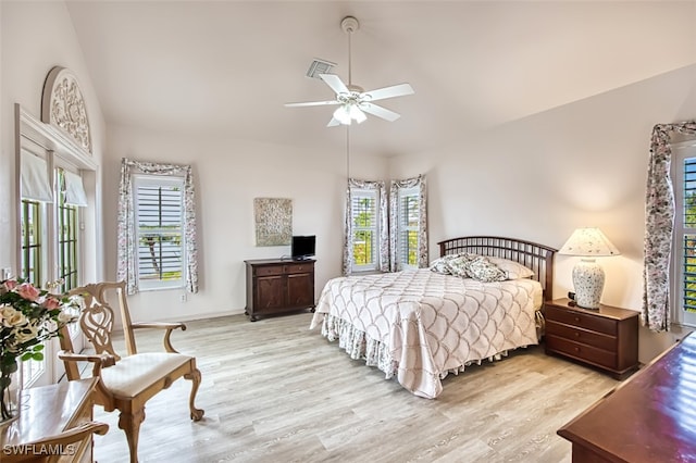 bedroom featuring multiple windows, lofted ceiling, and light hardwood / wood-style floors