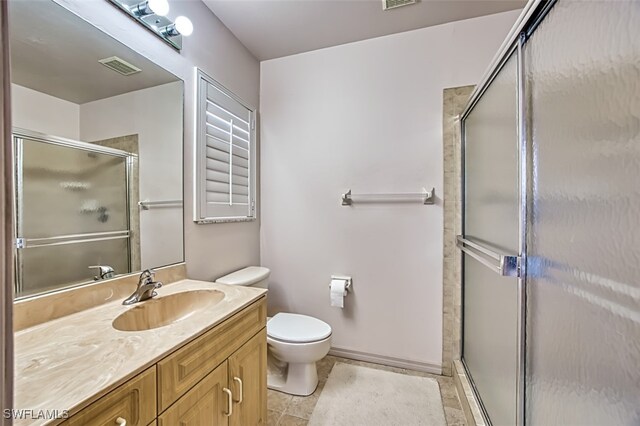 bathroom featuring a shower with door, vanity, tile patterned flooring, and toilet