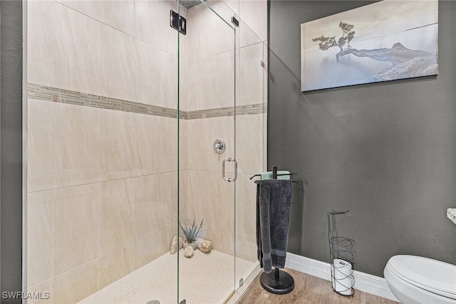 bathroom with a shower with shower door, toilet, and wood-type flooring