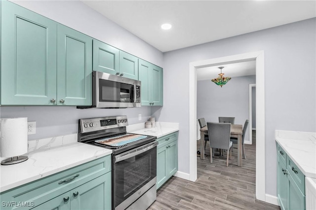 kitchen with light stone counters, stainless steel appliances, light hardwood / wood-style floors, and green cabinetry