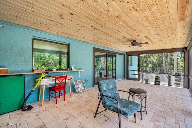 sunroom / solarium featuring plenty of natural light, wooden ceiling, and ceiling fan