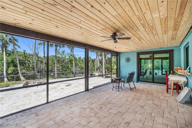 unfurnished sunroom featuring ceiling fan, plenty of natural light, and wooden ceiling