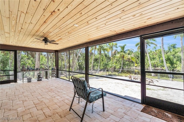 unfurnished sunroom featuring a wealth of natural light, wooden ceiling, and ceiling fan