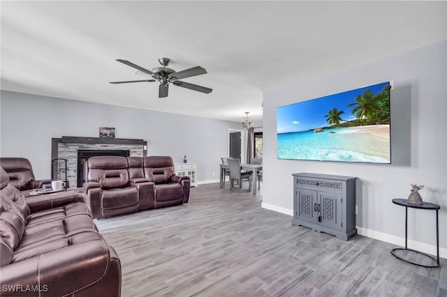 living room featuring ceiling fan with notable chandelier and light hardwood / wood-style flooring