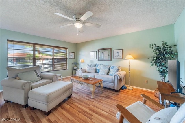 living room featuring ceiling fan, light hardwood / wood-style flooring, and a textured ceiling