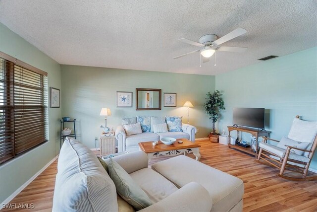 living room with ceiling fan, a textured ceiling, and light hardwood / wood-style floors