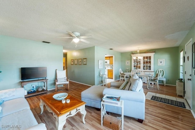 living room with ceiling fan, light hardwood / wood-style flooring, and a textured ceiling