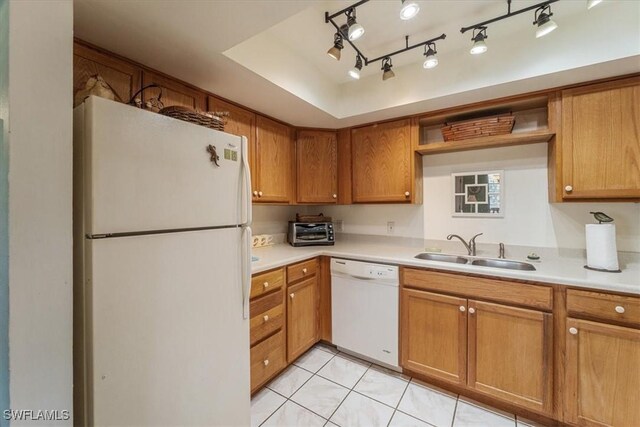 kitchen with a raised ceiling, sink, rail lighting, light tile patterned flooring, and white appliances