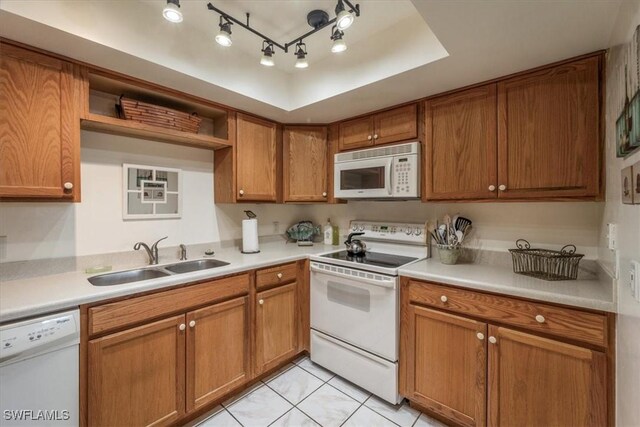 kitchen featuring sink, light tile patterned floors, track lighting, a tray ceiling, and white appliances