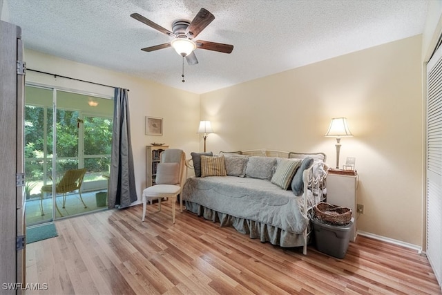 bedroom with ceiling fan, light hardwood / wood-style floors, and a textured ceiling