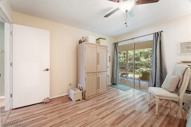 sitting room featuring ceiling fan, light hardwood / wood-style flooring, and a textured ceiling