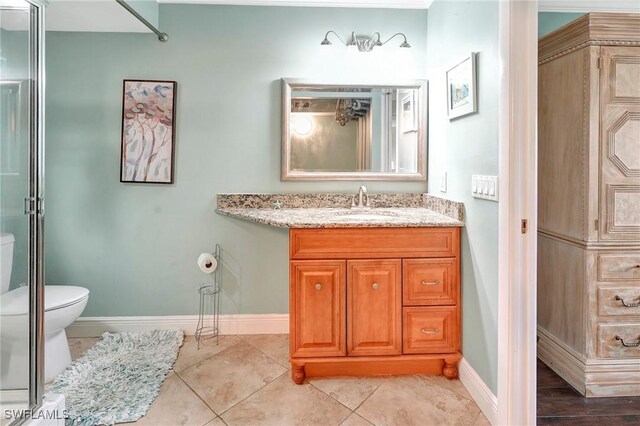 bathroom with tile patterned flooring, vanity, an enclosed shower, and toilet