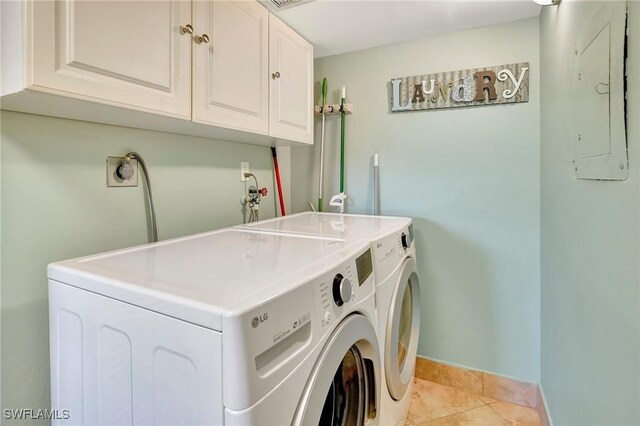 laundry area featuring light tile patterned flooring, cabinets, electric panel, and washer and dryer