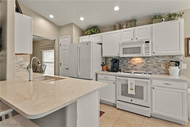 kitchen with white cabinetry, sink, a kitchen breakfast bar, kitchen peninsula, and white appliances