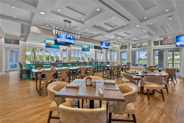 dining area with coffered ceiling, a towering ceiling, light wood-type flooring, and french doors