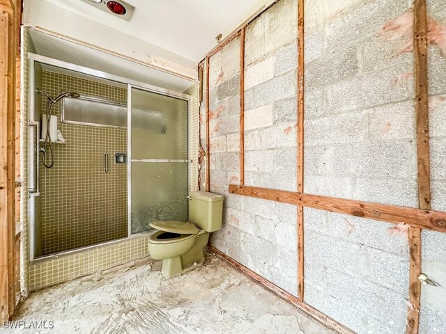 bathroom featuring a shower with door and toilet