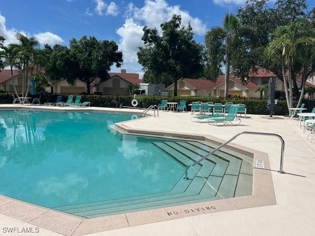 community pool with a patio area and fence