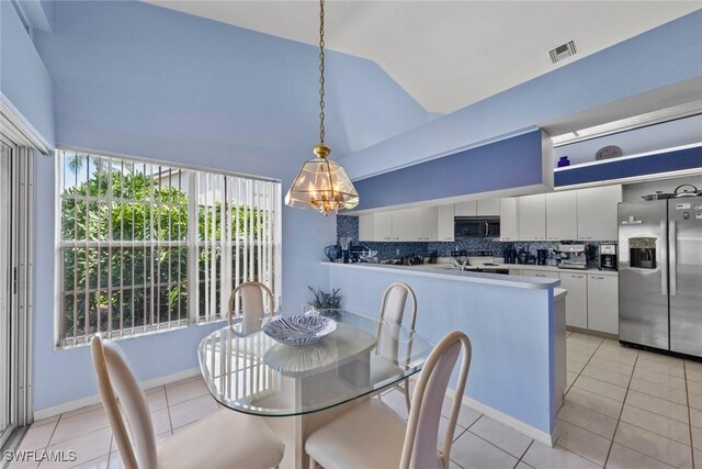 tiled dining room with lofted ceiling and an inviting chandelier