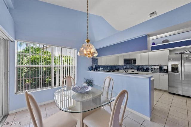 kitchen featuring light tile patterned floors, visible vents, decorative backsplash, vaulted ceiling, and stainless steel fridge