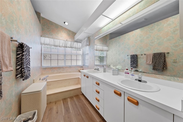 bathroom featuring vanity, hardwood / wood-style floors, lofted ceiling, and a bathing tub