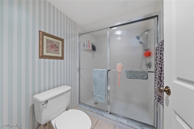 bathroom featuring a shower with door and toilet