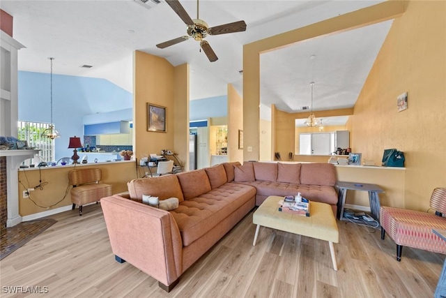 living area with high vaulted ceiling, ceiling fan with notable chandelier, wood finished floors, visible vents, and baseboards