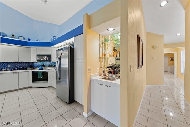 kitchen with black microwave, light tile patterned flooring, electric range, light countertops, and stainless steel fridge