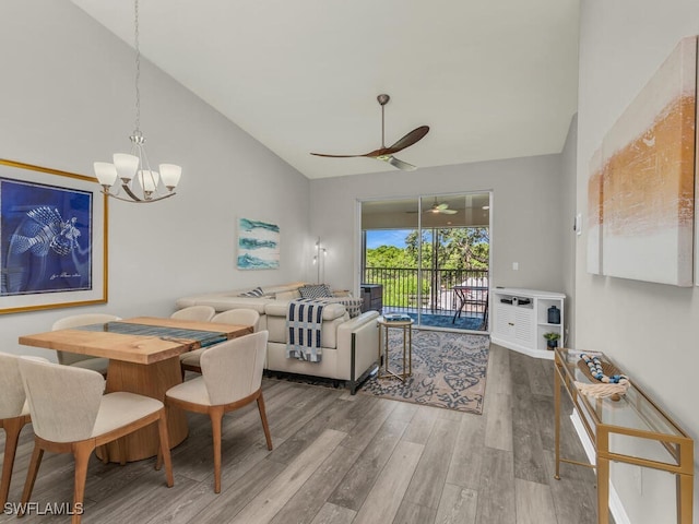 dining area with hardwood / wood-style flooring, ceiling fan with notable chandelier, and high vaulted ceiling