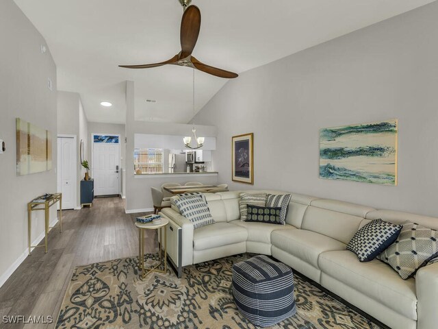 living room with hardwood / wood-style flooring, lofted ceiling, and ceiling fan with notable chandelier