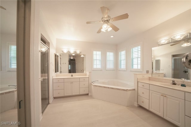 bathroom featuring double vanity, tiled tub, and ceiling fan