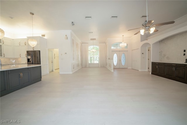 unfurnished living room with ceiling fan with notable chandelier and ornamental molding