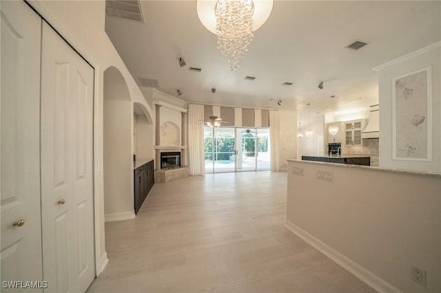 kitchen featuring tasteful backsplash, light wood-type flooring, ceiling fan with notable chandelier, ornamental molding, and white cabinets