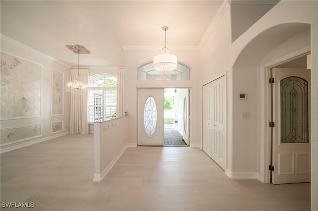 entryway with ornamental molding, an inviting chandelier, and light hardwood / wood-style floors