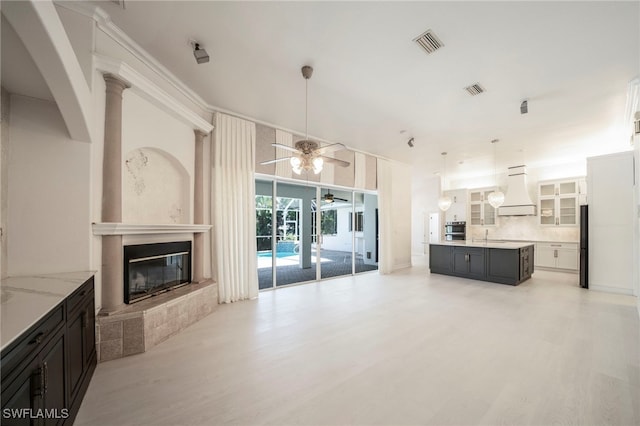 living room featuring ceiling fan, decorative columns, and light hardwood / wood-style floors