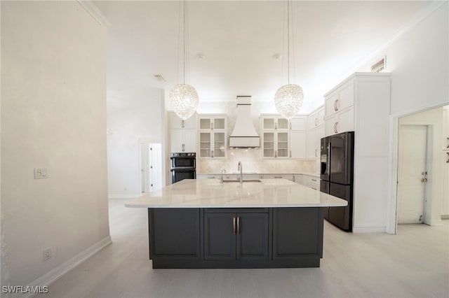 kitchen featuring tasteful backsplash, pendant lighting, black appliances, white cabinets, and custom range hood