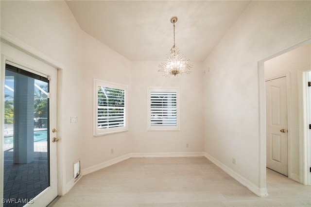 spare room featuring lofted ceiling and an inviting chandelier