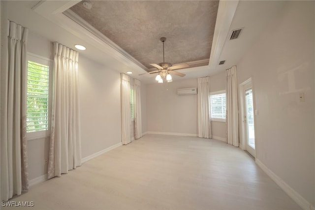 spare room featuring light hardwood / wood-style flooring, a wealth of natural light, and a raised ceiling