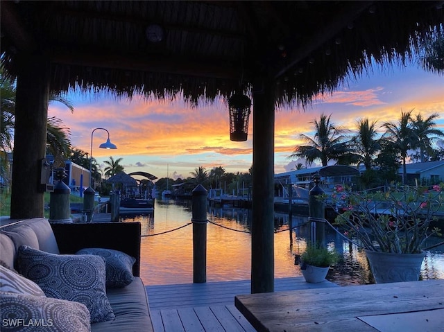 deck at dusk with a water view and a boat dock