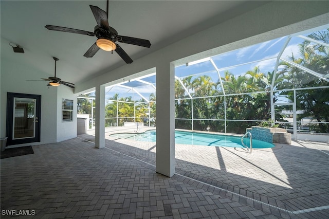 view of pool with glass enclosure, a patio area, and ceiling fan