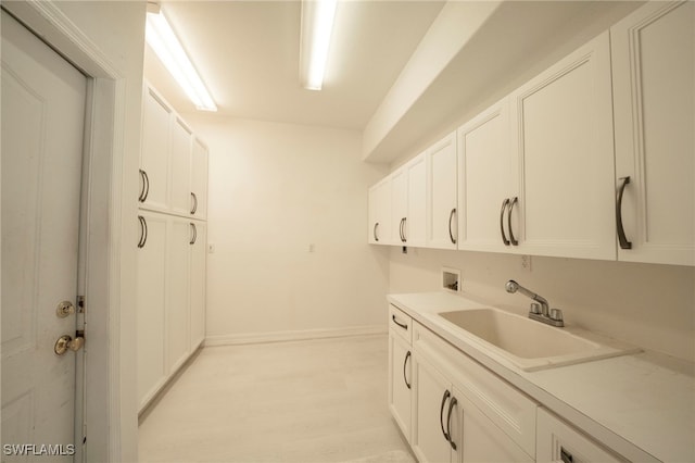 clothes washing area with hookup for a washing machine, sink, cabinets, and light hardwood / wood-style floors